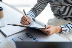 Business woman hand writing on a notepad with a pen in work office.